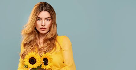 Delicate red hair woman with natural freckles holding beautfiul sunflowers.の写真素材