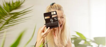 Young blonde girl photographing , smiling. Hobby concept.