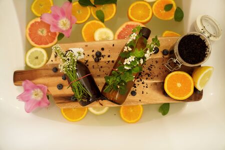 Relaxing bath with grapefruit, lemon, oranges slices and flowers. Beauty treatment. Wellness, zero waste concept.の写真素材