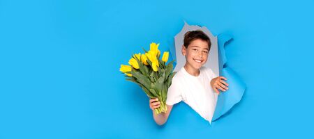Smiling child boy with bouquet of yellow tulip flowers. Mother's Day Greeting Card. Happy mothers day.Women's Day. Copy space.の写真素材