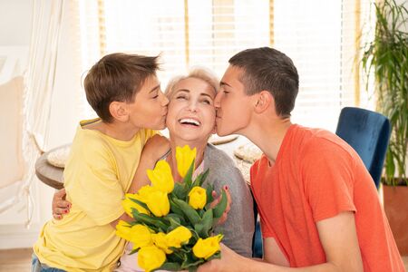 Mommy with kids sons smiling to the camera, posing at home. Mothers Day, love, family, parenthood, childhood concept.の写真素材