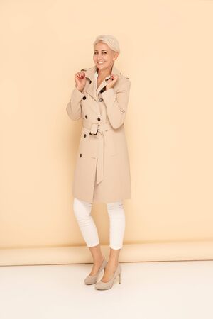 Elegant woman in trendy beige coat. Blonde short hair. Fashion spring lookbook.の写真素材