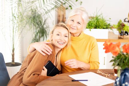 Senior beautiful woman spending time at home with her granddaughter, hugging, talking, smiling.の写真素材