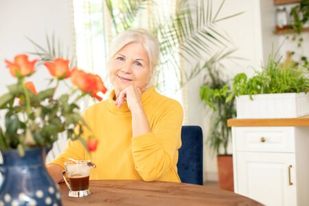 Happy smiling senior woman with hot coffee relaxing at home.