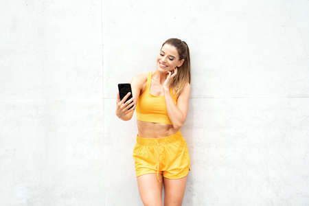 Photo of a pretty sports fitness woman outdoors using mobile phone after outdoor workout.