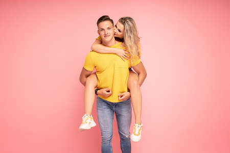Beautiful young couple smiling, posing on pink pastel studio background.の写真素材