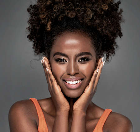 Beautiful african woman smiling and looking at camera with joy. Beauty afro american girl with curly...