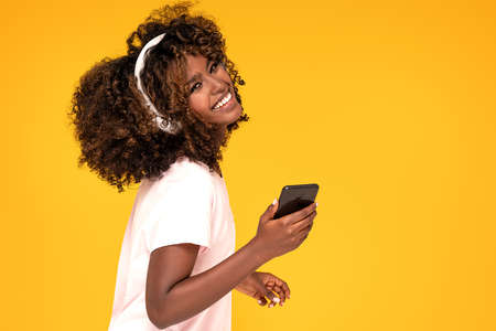 Cheerful beautiful african woman listening to music with headphones, dancing.