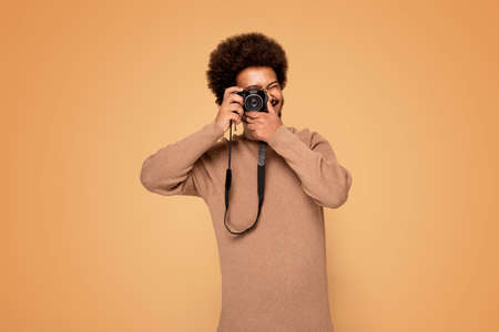 Cheerful afro guy taking photos with a camera.の写真素材