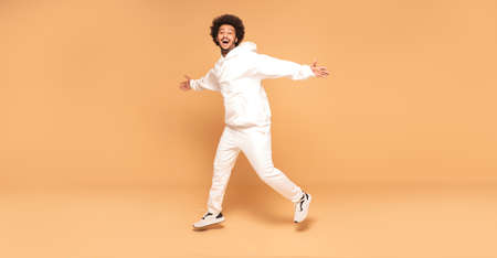 Positive afro man jumping up over studio background.の写真素材