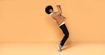 African man having fun during photoshoot in studio, dancing and smiling.の写真素材