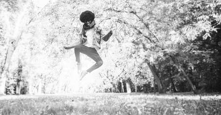 Young African American man jumping in park.の写真素材