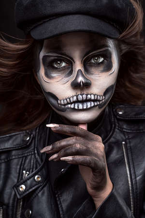 Portrait of a woman with skull makeup over black studio background. Halloween costume and make-up.