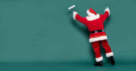 Christmas are coming! Real Santa Claus is getting ready for the season, painting the wall.の写真素材