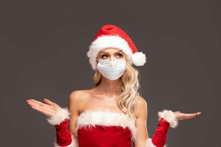 Woman in medical mask and christmas costume with both palms openedの写真素材