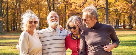 Group of Senior Retirement Friends smiling, spending time together in autumn beautiful park.