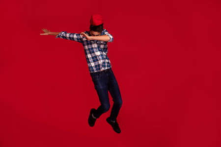 Full-length shot of a fashionable teenage boy jumping isolated on red background. Active lifestyle...