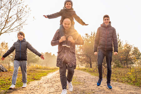 Happy family: father and children sons on a walk in nature on beautiful autumn sunset. Boys having...