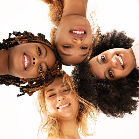 Group of four happy multiethnic friends looking at camera. Portrait of young women of different cultures enjoying time together. Young people lifestyle concept.の写真素材
