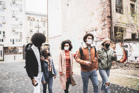 Group of multiracial happy friends walking outdoor, having fun together, wearing face masks....