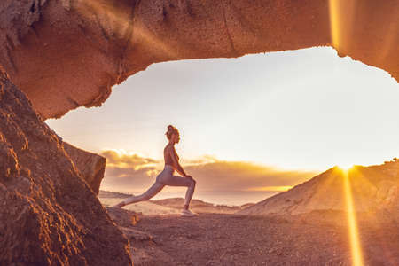 Woman doing yoga, stretching, meditating on the top of a mountain above clouds at sunrise. Zen,...