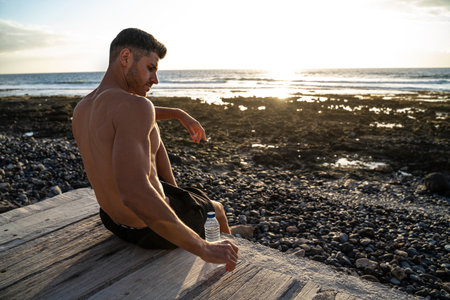 Fit young man relaxing after outdoor beach workout. Handsome young fitness man. Sports and active lifestyle concept.の写真素材