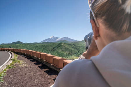 Tourist woman looking through binoculars at volcano while traveling on Teide national park on...