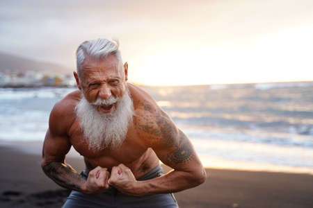 Fit and muscular senior man exercising on the beach. In a healthy body, healthy mind. Age is just a number. People on retirement.の写真素材