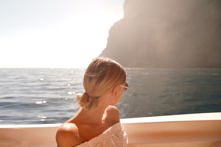 Joyful woman on sailing boat discovering island coast on summer cruise. Travel adventure, relax time. Summer vibes.の写真素材