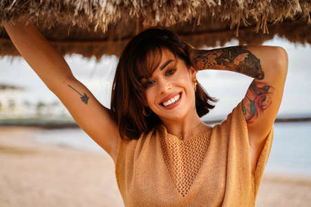 Beautiful smiling woman portrait in sunset on the beach. Girl with tattoos. Real people lifestyle....
