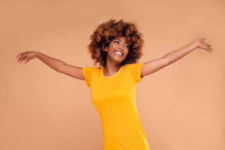 Beautiful african american woman smiling and dancing, full of joy and happiness. Real people emotions. Girl with afro hairstyle and delicate makeup. Natural beauty.の写真素材