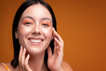 Young natural woman with beauty face touching healthy facial skin. Beautiful smiling girl model with...