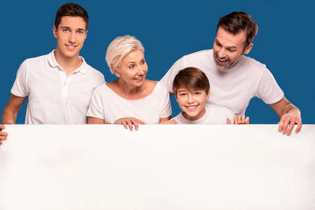 A wonderful happy family wearing white tshirts- two sons, mom and dad. Smiling, friendly people pose...