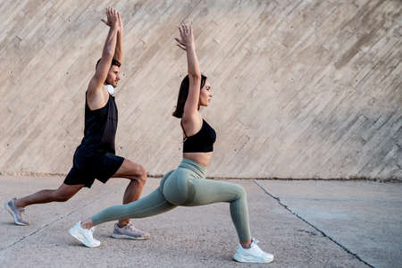 Female physical, personal trainer doing outdoor workout with one man. Stretching exercises, yoga....