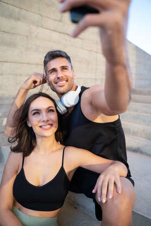 Attractive happy couple taking a selfie with a smartphone after outdoor workout. Sport and healthy lifestyle concept. Personal Trainer. Morning routine.の写真素材