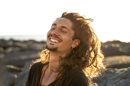 Portrait of happy handsome hippie italian man with long hair smiling beautiful. Freedom. Wanderlust. Tropics. Traveler.Beach. Relax. Tourism.の写真素材