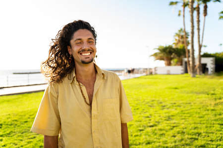 Portrait of handsome hippie italian man with long hair smiling beautiful to the camera. Tourist. Tourism. Wanderlust. Tropics. Traveler.の写真素材
