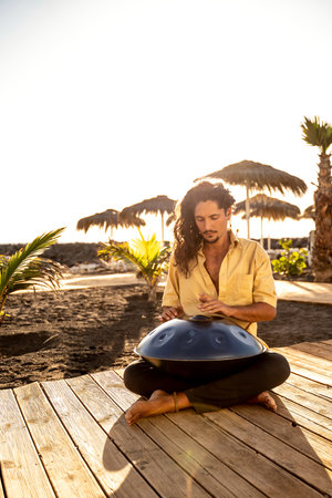 Handsome italian man practicing native music on a hang drum, a traditional drumming instrument...