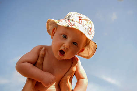Funny little baby boy in summer cap over blue sky background. A lot of copy space.