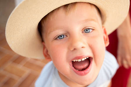 Happy child boy with big beautiful smile and blue eyes wearing summer hat. Real people emotions.