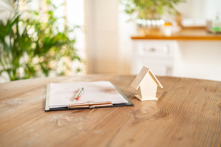 Wooden small model house and documents on the desk. Home insurance, investment, rental or purchase real estate and mortgages. House trading ideas.の写真素材