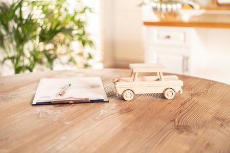 The wooden car's model and documents on the desk. Insurance details, car rental. Safe Vehicle Concept.の写真素材