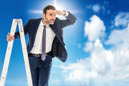 Handsome confident businessman leader climb up to reach top of ladder high in the sky. Ladder of success, vision to lead business to achieve goal or opportunity in career concept. A lot of copy space.の写真素材