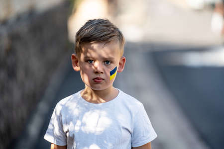 Child against war. Upset , angry Ukrainian boy with bue yellow flag on his face protesting war conflict. Evacuation of civilians. Freedom to Ukraine. Stop Russian aggression. Stop war Ukraine Russia. Support Ukraine.の写真素材