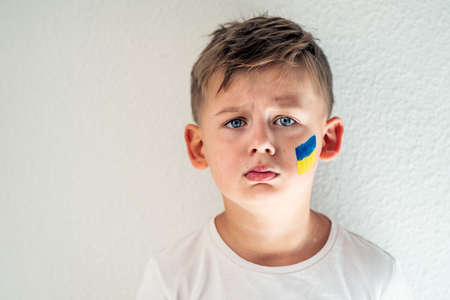 Child against war. Upset , angry Ukrainian boy with bue yellow flag on his face protesting war conflict. Evacuation of civilians. Freedom to Ukraine. Stop Russian aggression. Stop war Ukraine Russia. Support Ukraine.の写真素材