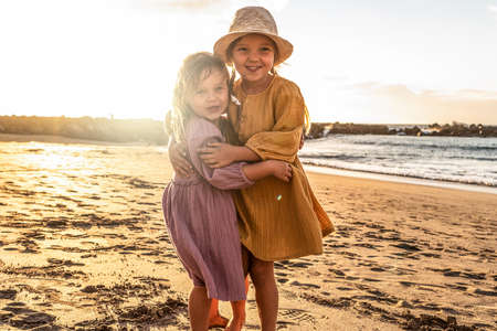 Lovely little sisters having fun at the beach, sunset summer time. A lot of copy space. Travel. Tourist.の写真素材