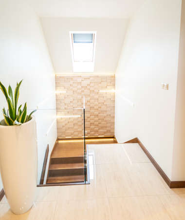 Photo of bright beautiful, modern home interior with natural light. Corridor with a wooden stairs and glass railing.の写真素材