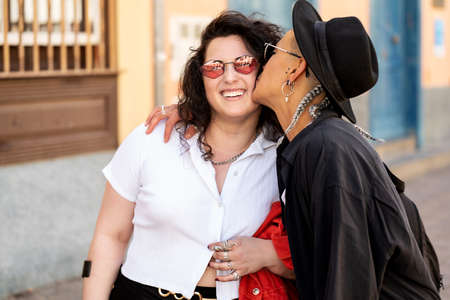 Young loving lesbian couple hugging and kissing on the city street. Romantic date. Real people emotions.の写真素材