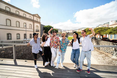 Group of young fashionable friends spending time together in the city, walking, talking and...