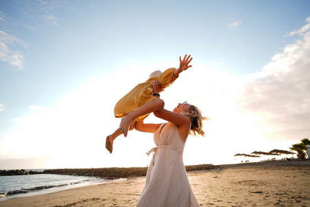 Happy mother with her little daughter having fun together on the beach, playing and laughing. A lot of copy space. Family summer vacations. Mother's day. Children's day. Real people emotions.の写真素材